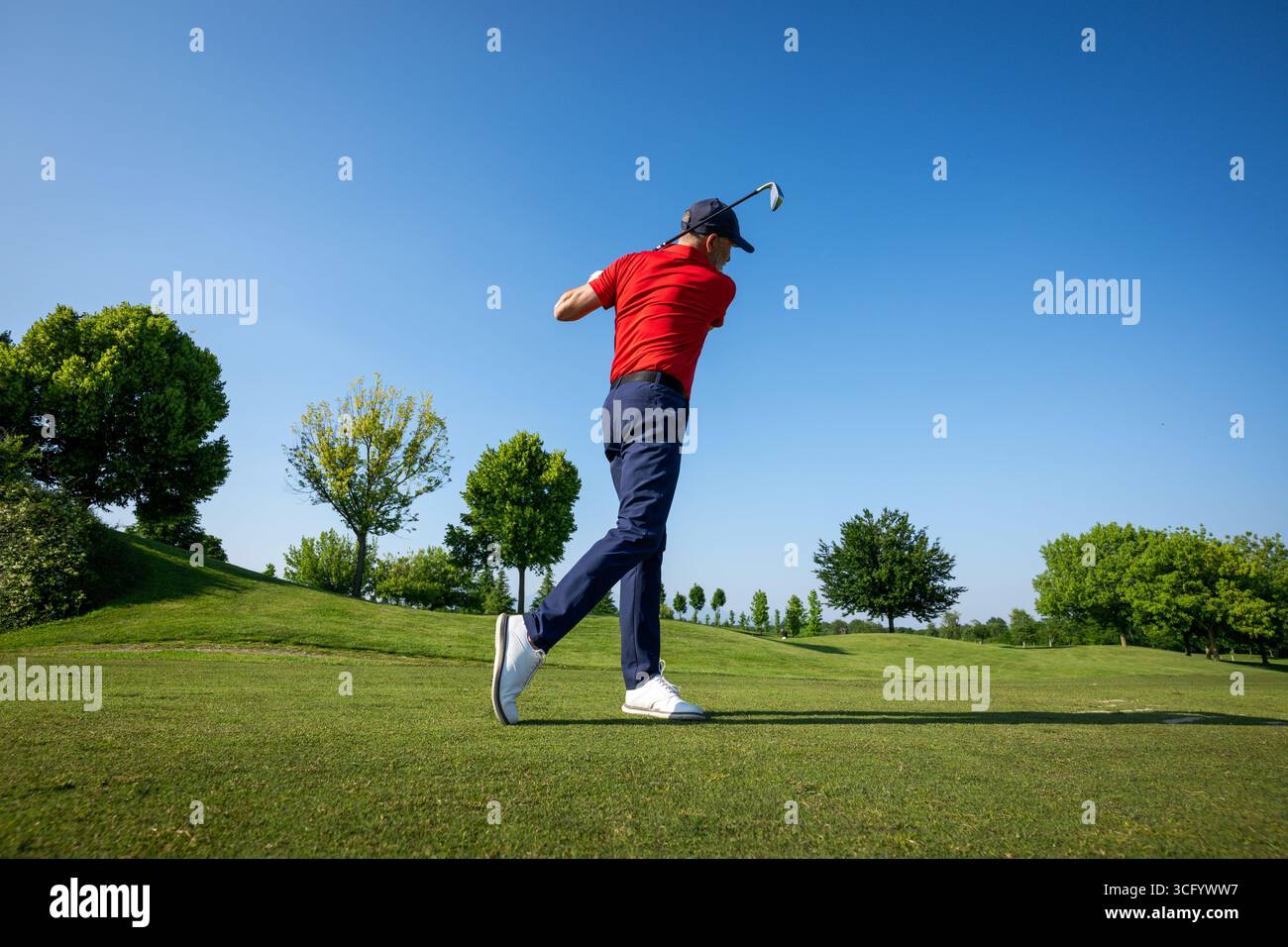 Golfista professionista che fa oscillare il suo club in una bella giornata di sole sul campo da golf Foto Stock