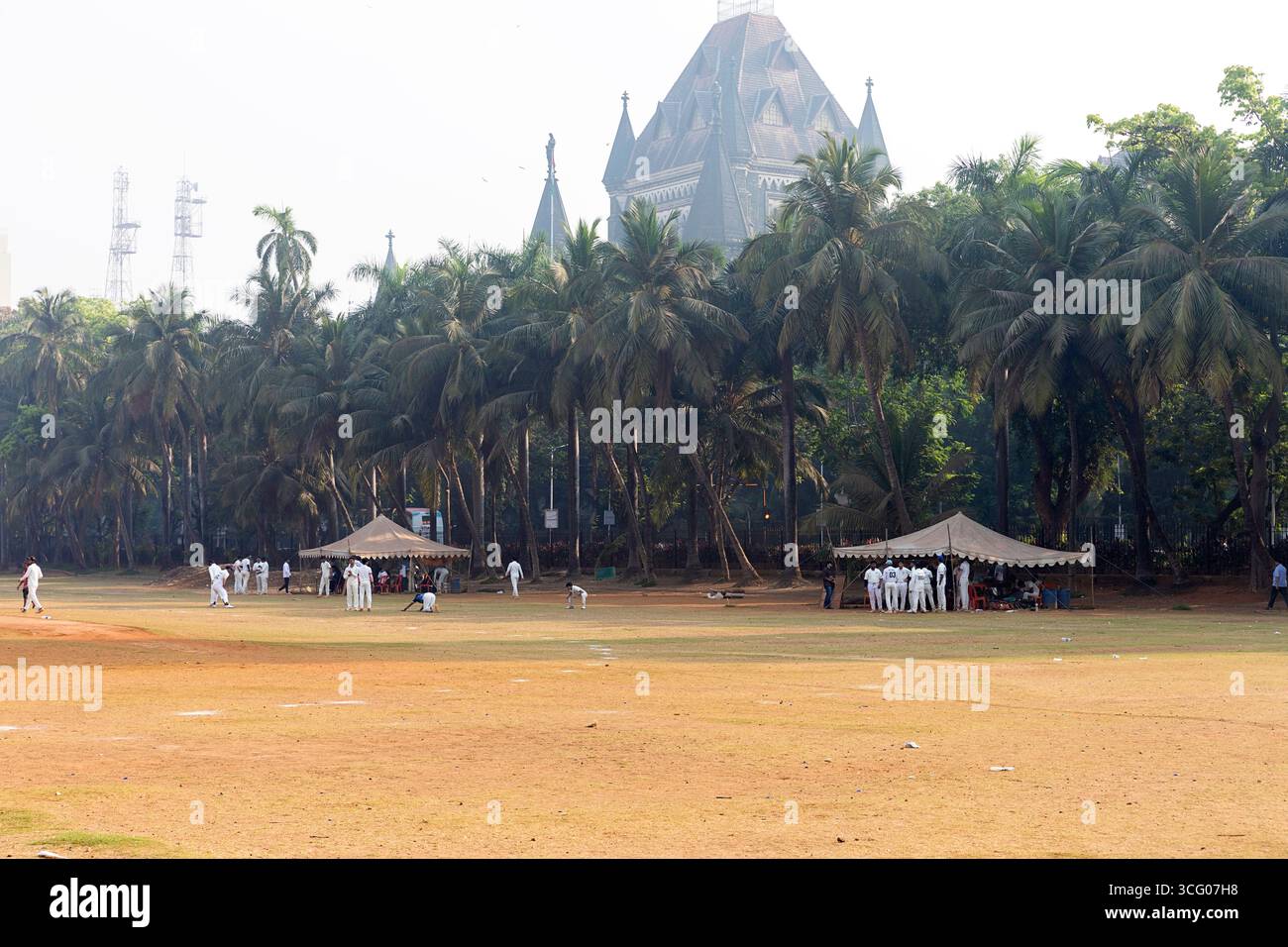 Persone che si preparano per una partita di cricket nel parco Oval Maidan, Bombay, Mumbai, India, con l'edificio HIGH COURT OF BOMBAY sul retro Foto Stock