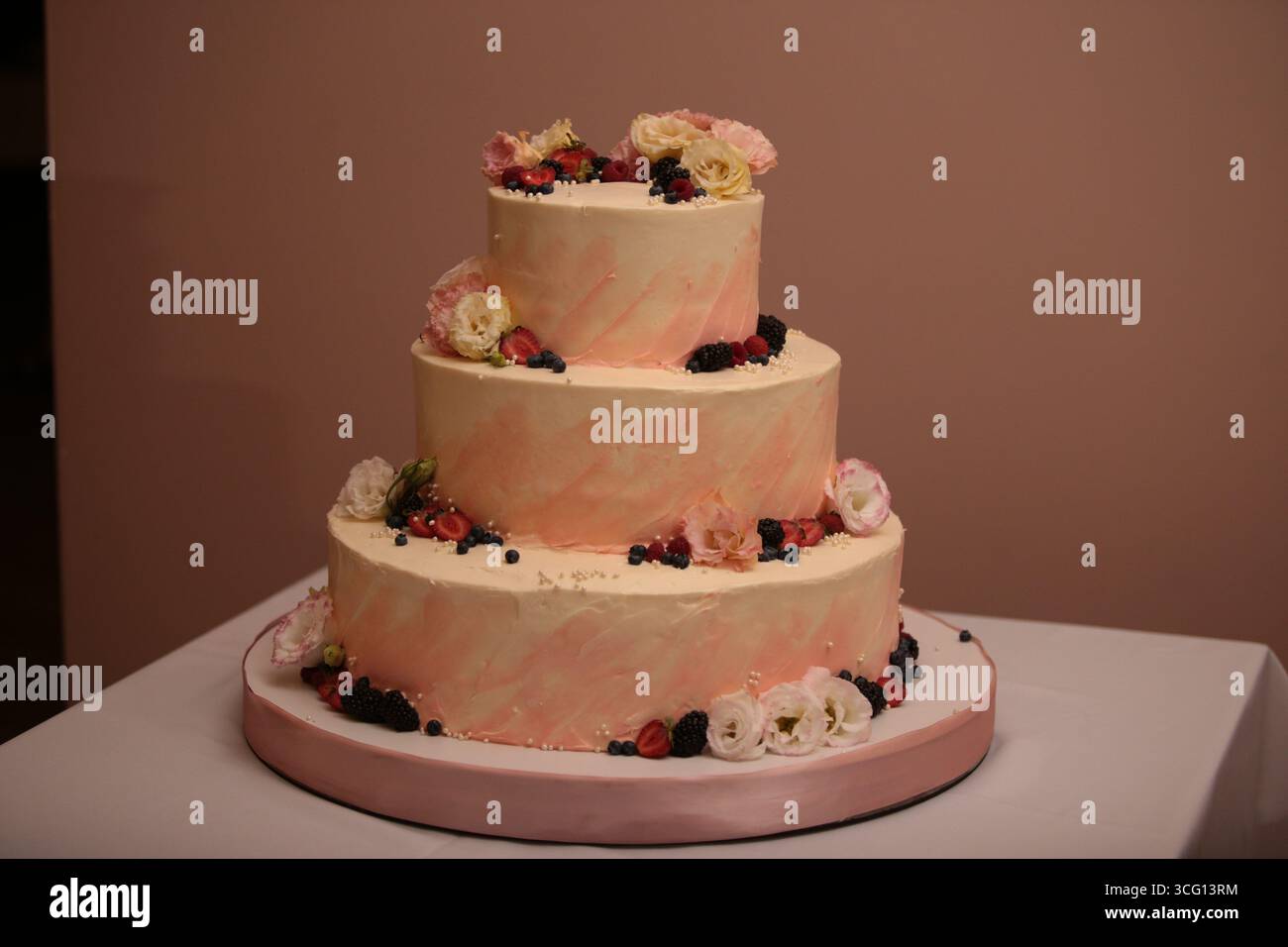 Banchetto splendidamente decorato torta nuziale bianca festiva con rose, frutti di bosco e fiori di frutta Foto Stock