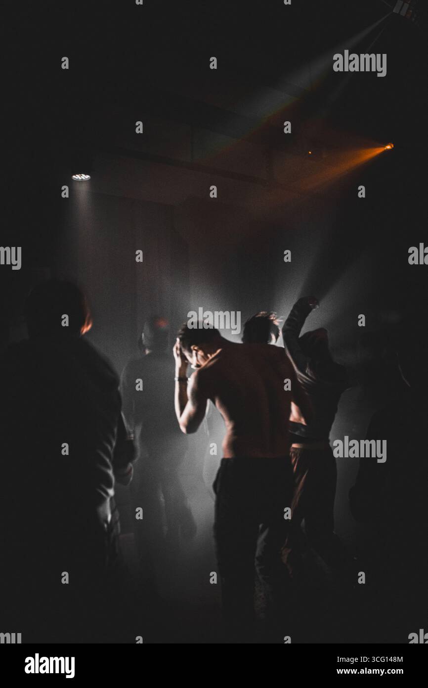 DJ set. Gente che ballava al rave al buio. in fumo bianco. Disc jockey professionale che mixa brani musicali. Tecno duro Foto Stock