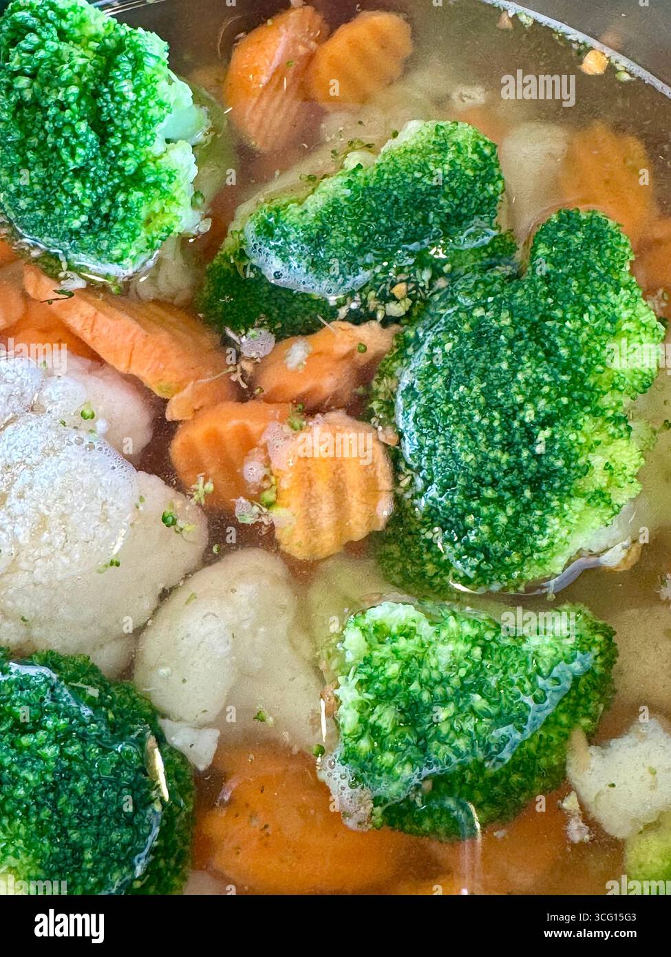 Primo piano di broccoli, carote e cavolfiore bolliti in acqua durante la cottura. - Immagine stock catturata con smartphone