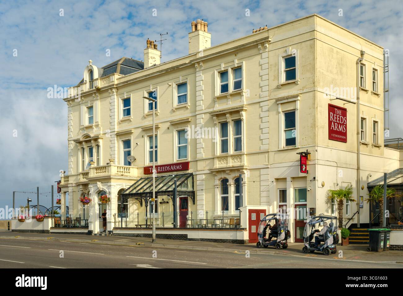Burnham-on-Sea, Somerset - due scooter mobili passano davanti al Reeds Arms, un popolare pub Wetherspoon a Burnham-on-Sea nel Somerset, Inghilterra. Foto Stock