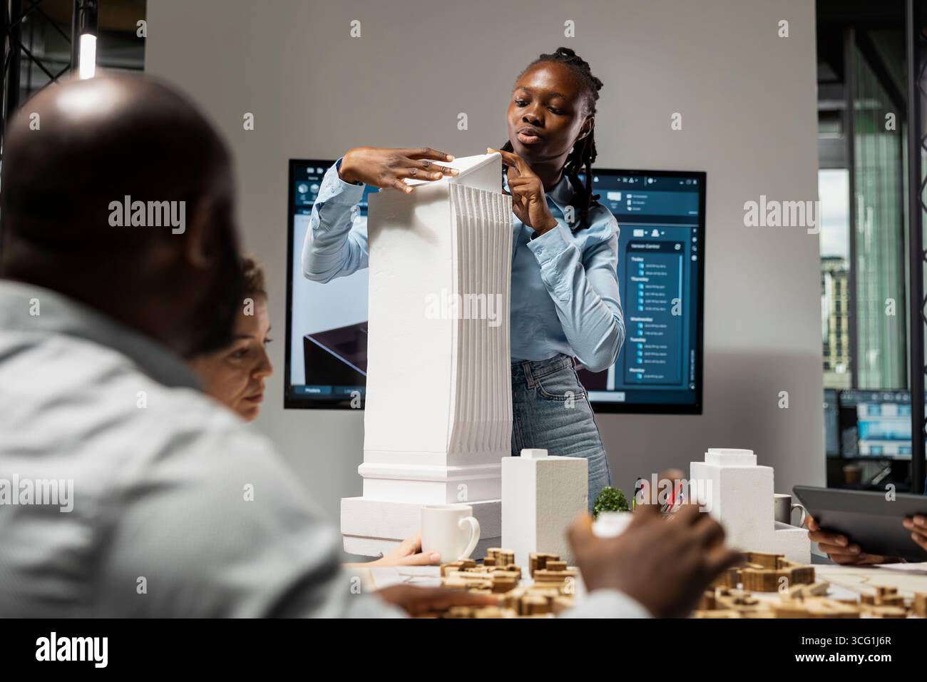 L'appaltatore afroamericano mostra modelli 3D architettonici per il futuro cantiere, lavoro di squadra per un nuovo progetto immobiliare. Piano generale per la progettazione di un progetto residenziale, pianificazione urbana. Foto Stock