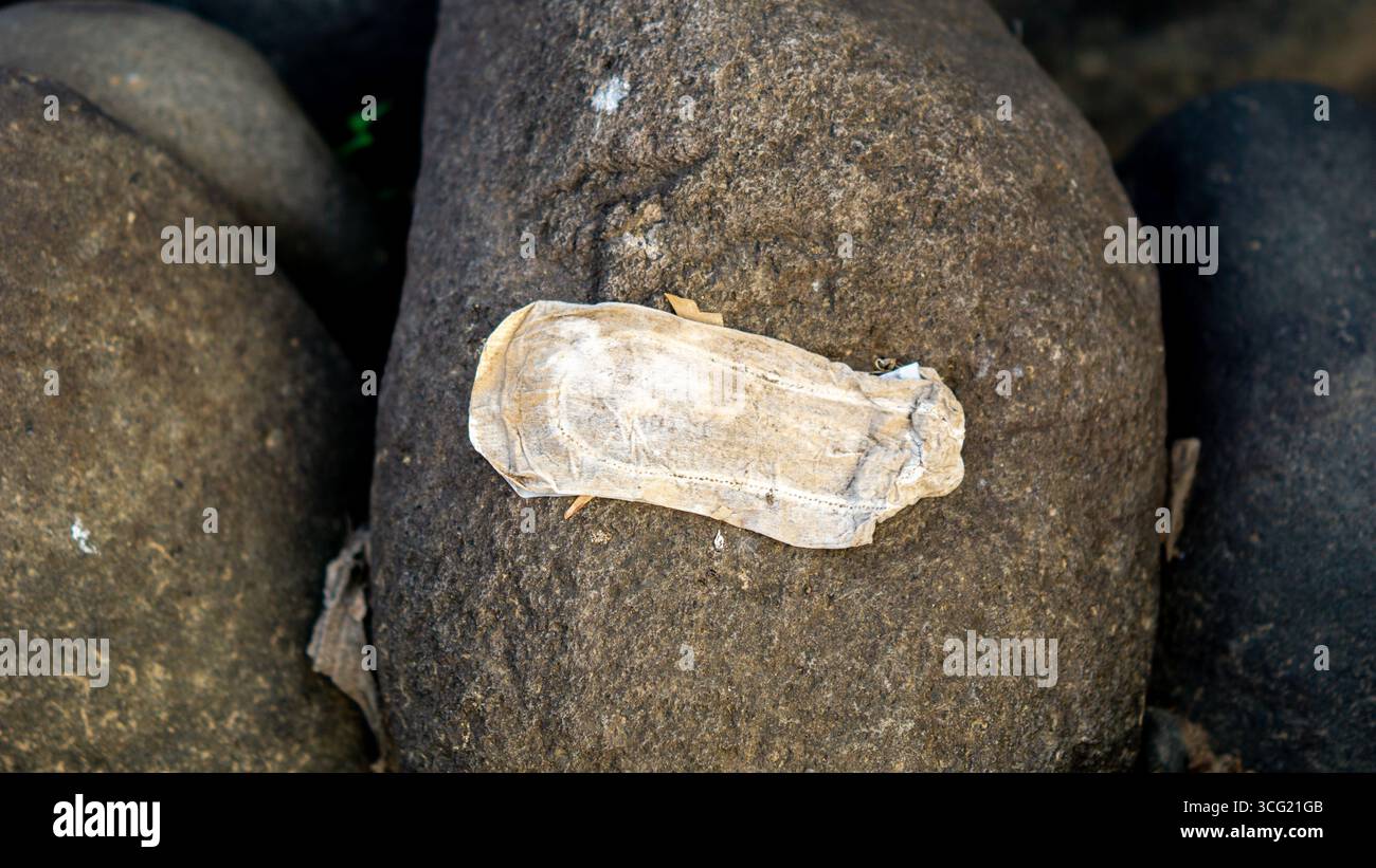 I tamponi mestruali usati si trovano sulle rocce del fiume. sembra sporco e disgustoso. Foto Stock