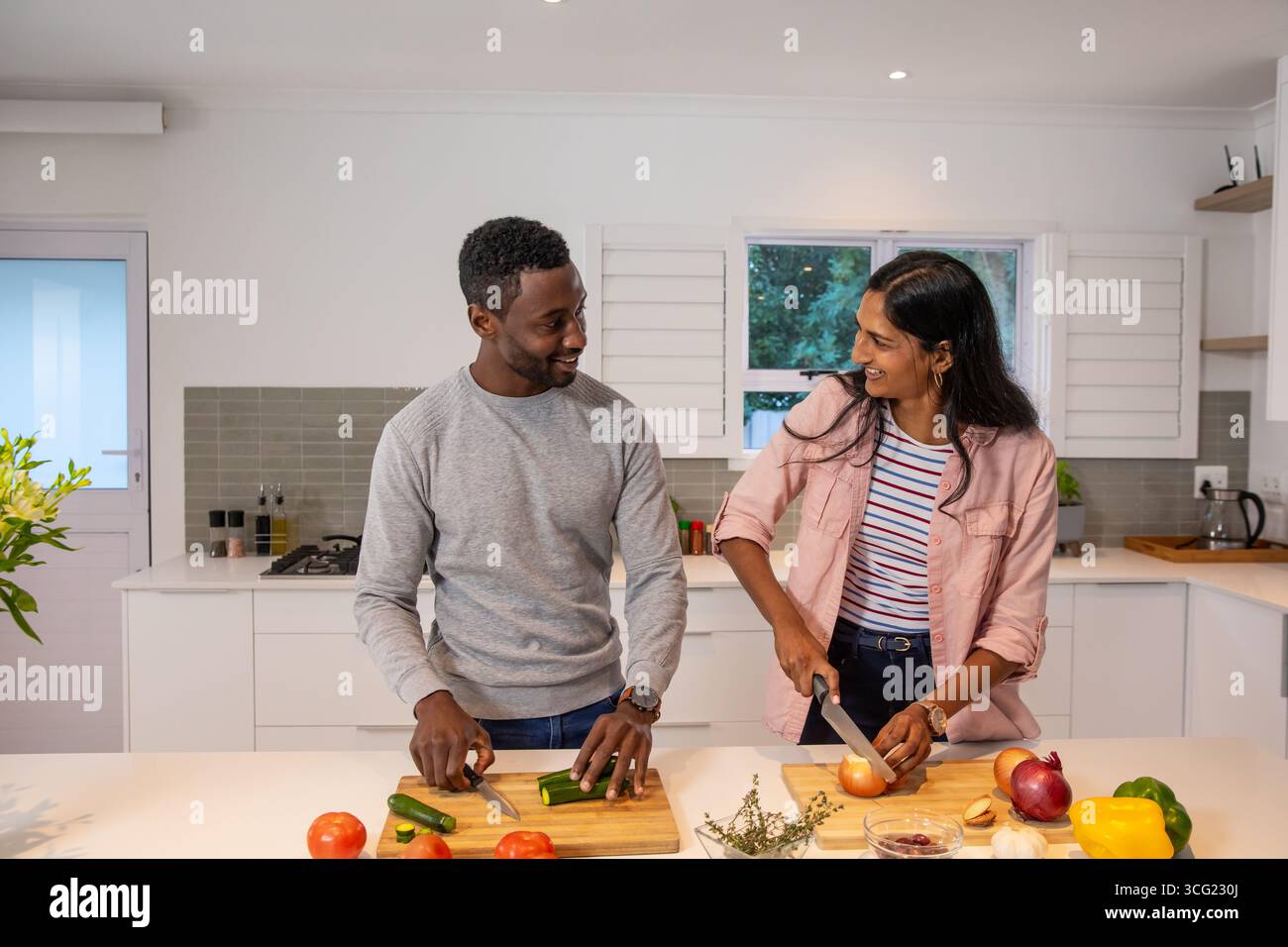 Diverse coppie al banco della cucina di casa tritare verdure fresche su taglieri di legno Foto Stock