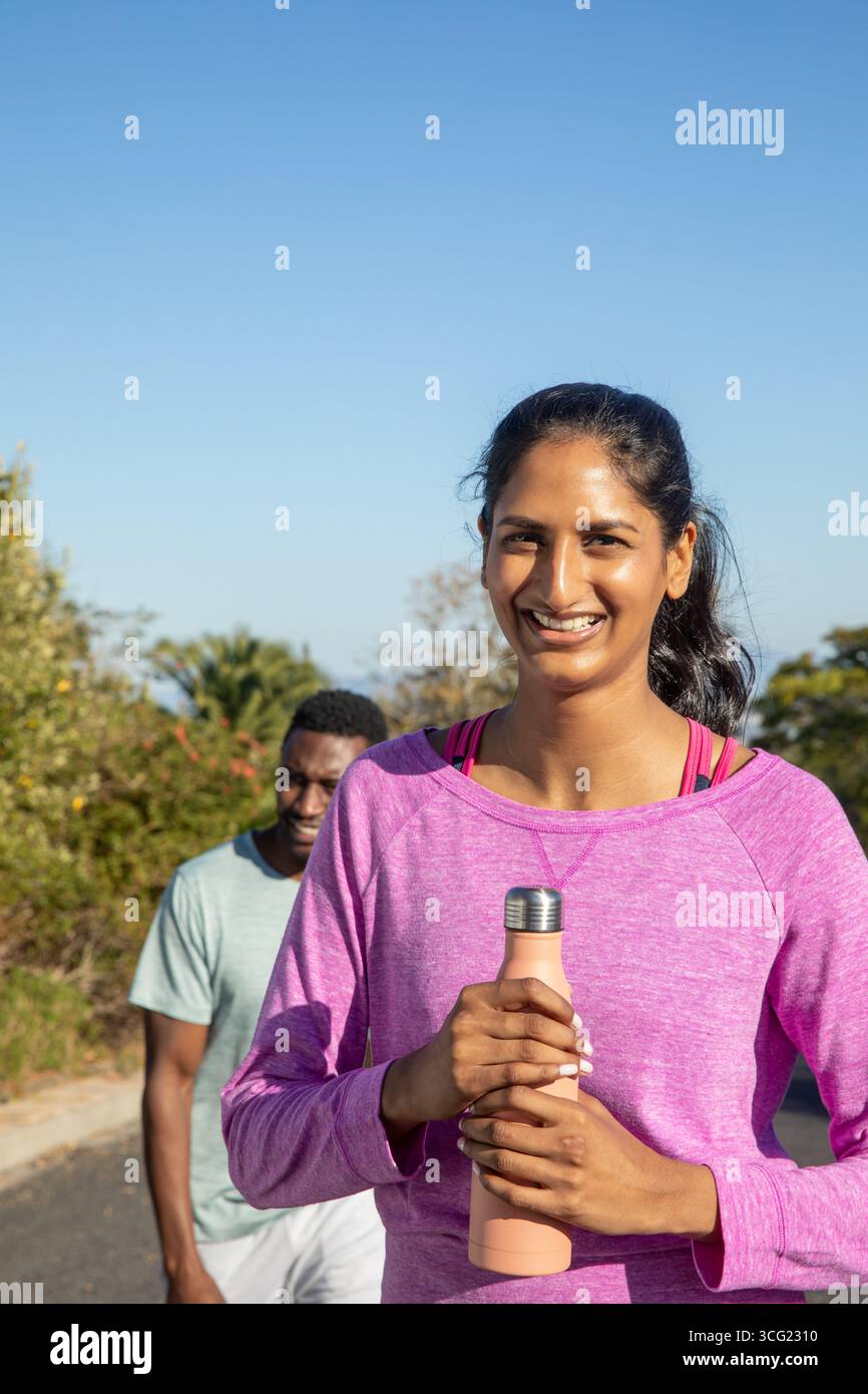 Amici diversi che fanno jogging sul sentiero, donna indiana in rosa con bottiglia d'acqua di pesca, spazio copia Foto Stock