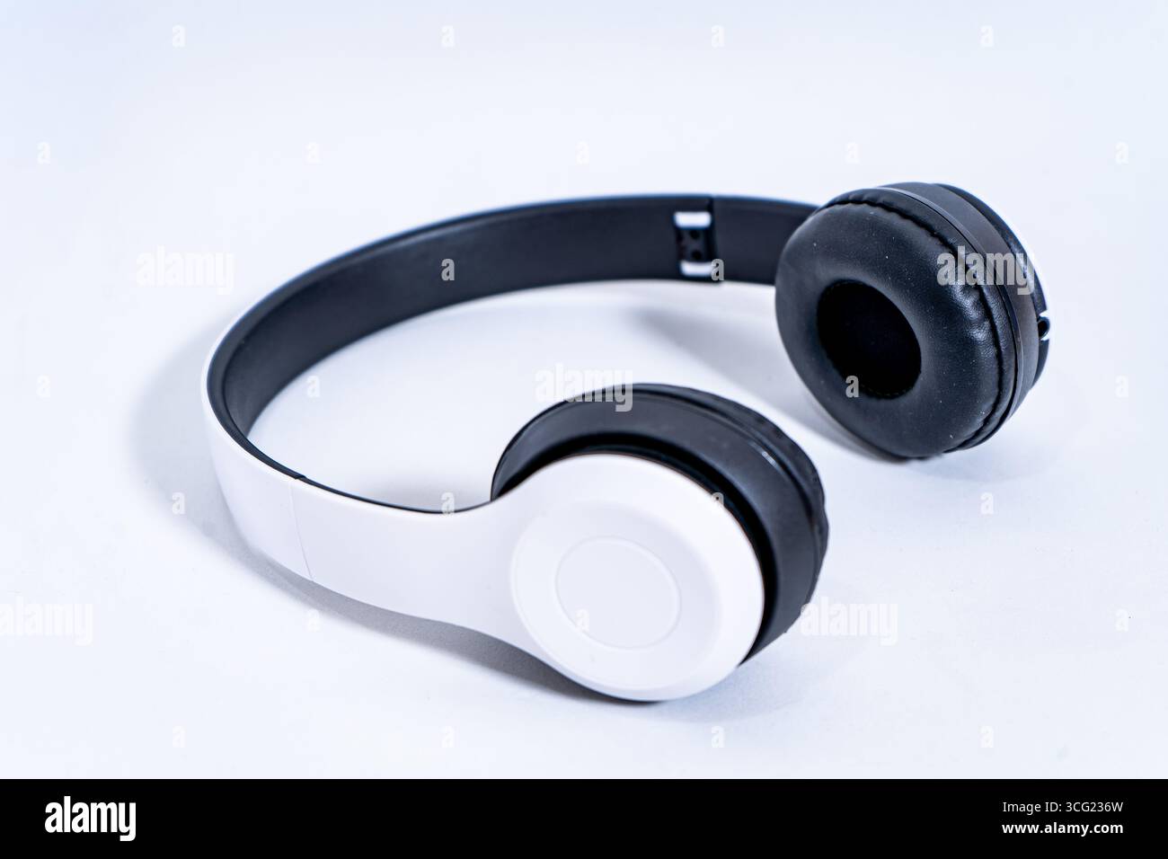 Cuffie wireless in bianco e nero posizionate su uno sfondo bianco minimalista, che rappresentano l'ascolto di musica, il piacere del podcast e la comunicazione audio Foto Stock
