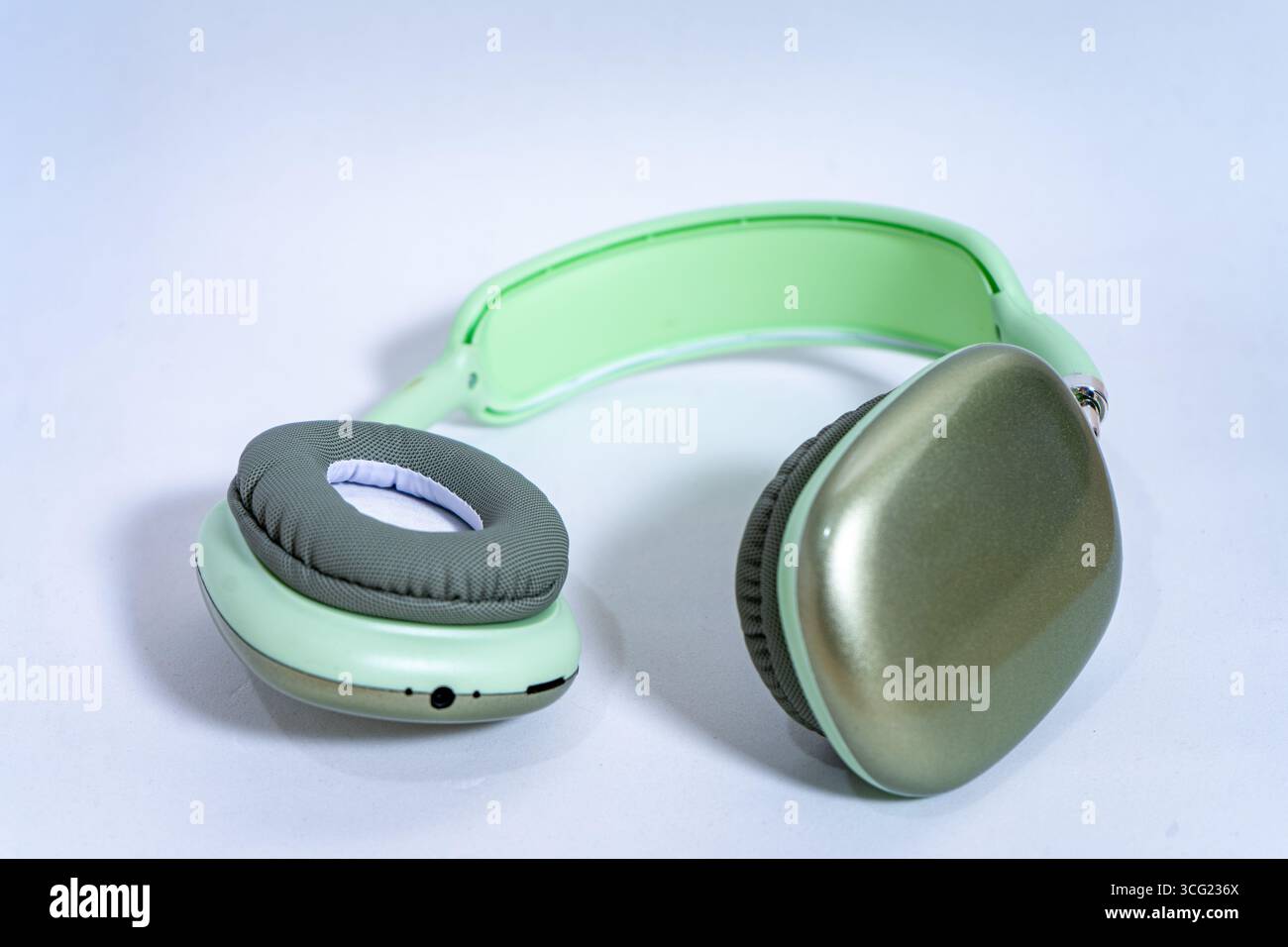 Eleganti cuffie wireless color verde pastello isolate su uno sfondo bianco, che rappresentano musica, tecnologia e divertimento audio Foto Stock