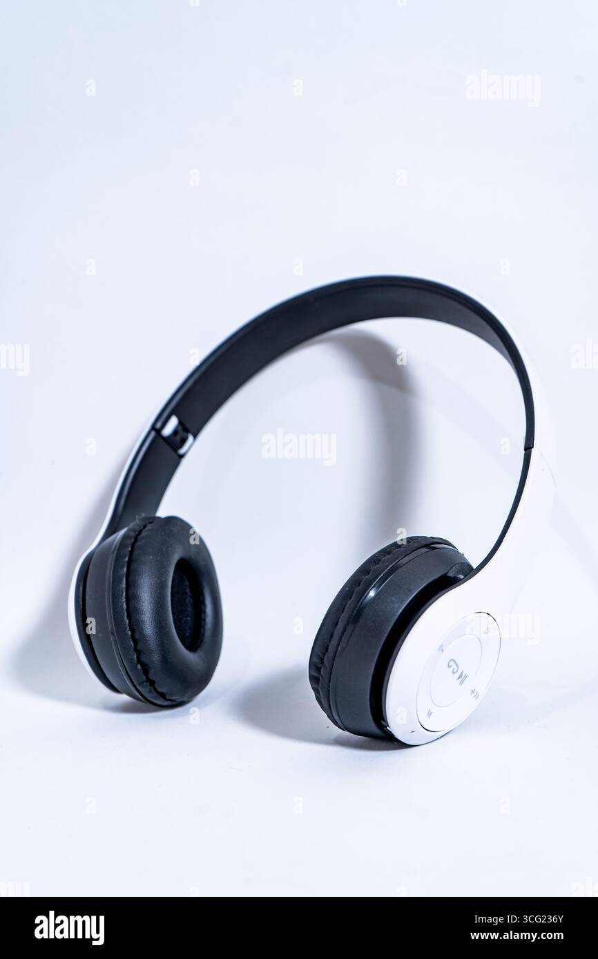 Le cuffie wireless in bianco e nero sono visualizzate su uno sfondo bianco minimalista, sottolineando la portabilità e la qualità audio Foto Stock