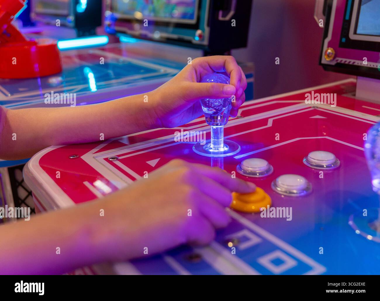 Le mani di una persona afferrano il joystick e premono i pulsanti su un computer arcade. Nostalgia, divertimento e intrattenimento dai classici giochi arcade Foto Stock