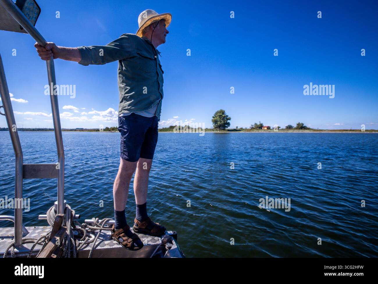 Hohen Wieschendorf, Germania. 18 agosto 2025. Matthias Braun, presidente dell'associazione di conservazione del paesaggio Dummersdorfer Ufer, è alla ricerca di un comodo ormeggio per la barca da lavoro "Limosa". Un totale di 22 capre saranno trasportate attraverso la Baia di Wismar fino all'isola di Walfisch, riserva ornitologica di otto ettari. Dopo la fine della stagione di riproduzione degli uccelli marini, le capre saranno utilizzate come ambientalisti per falciare piante e cespugli sull'isola nel Mar Baltico. Crediti: Jens Büttner/dpa/Alamy Live News Foto Stock