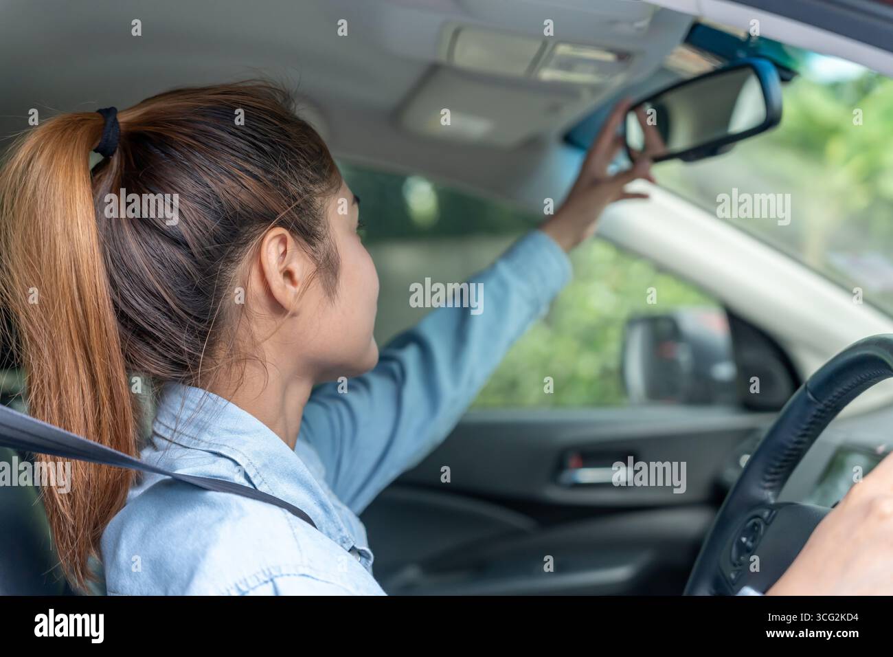 donna regola lo specchietto retrovisore dell'auto prima della guida, guida con intento, guida sicura, pratica di guida, donna allegra seduto comodamente sul sedile del conducente wi Foto Stock