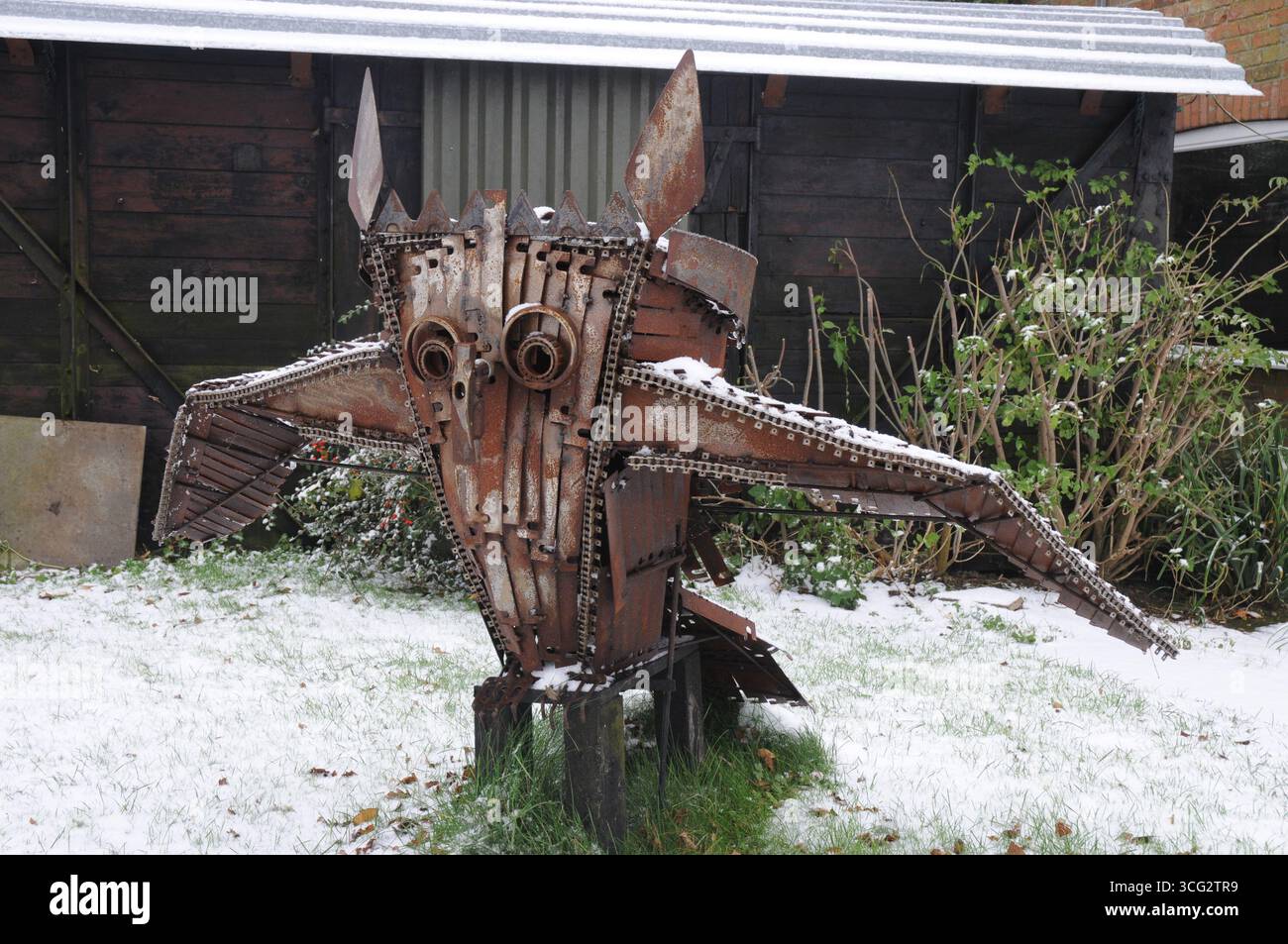 Una scultura in metallo dal design complesso a forma di gufo è posizionata in un giardino innevato, che mostra artigianato artistico in mezzo alla natura. Foto Stock