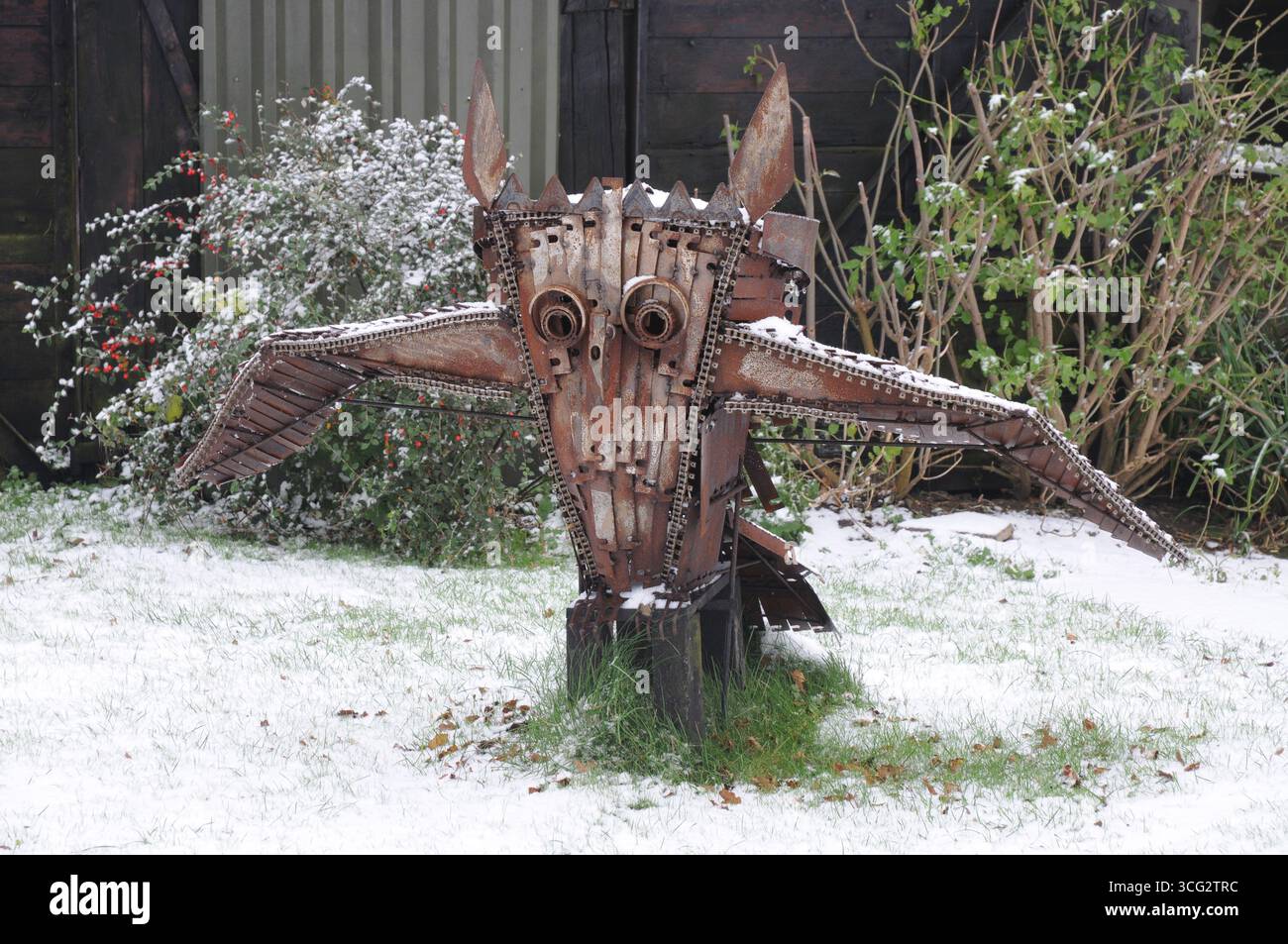 Una scultura in metallo unica è all'aperto, circondata da neve fresca e vegetazione, che mostra arte alla luce dell'inverno. Foto Stock