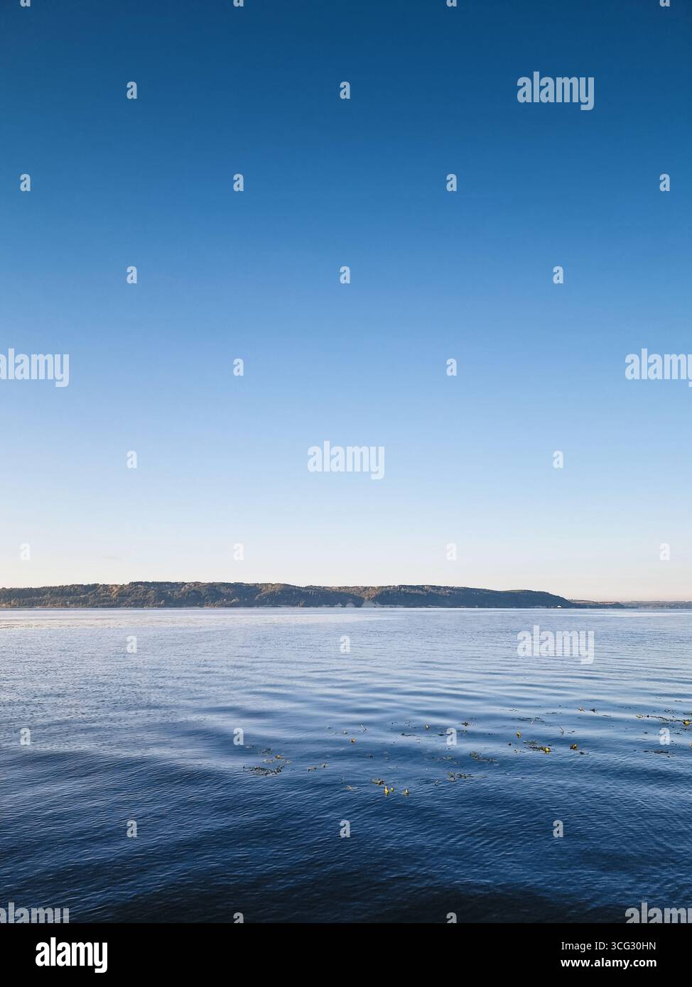 Lago in mattinata. Macchina fotografica vicino alla superficie dell'acqua calma del grande lago poco dopo l'alba. Cielo in pendenza sopra la riva montana del fiume. Foto Stock