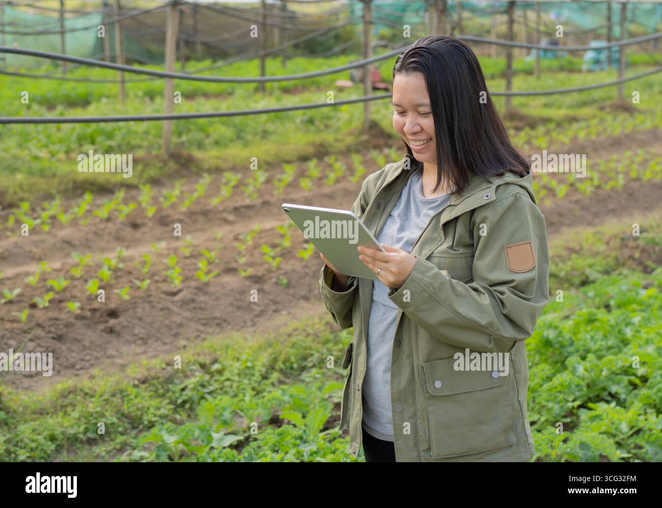 Ritratto con vista laterale del lavoratore sorridente del giardino con tablet digitale a Greenhouse. Copia sapce. Foto Stock