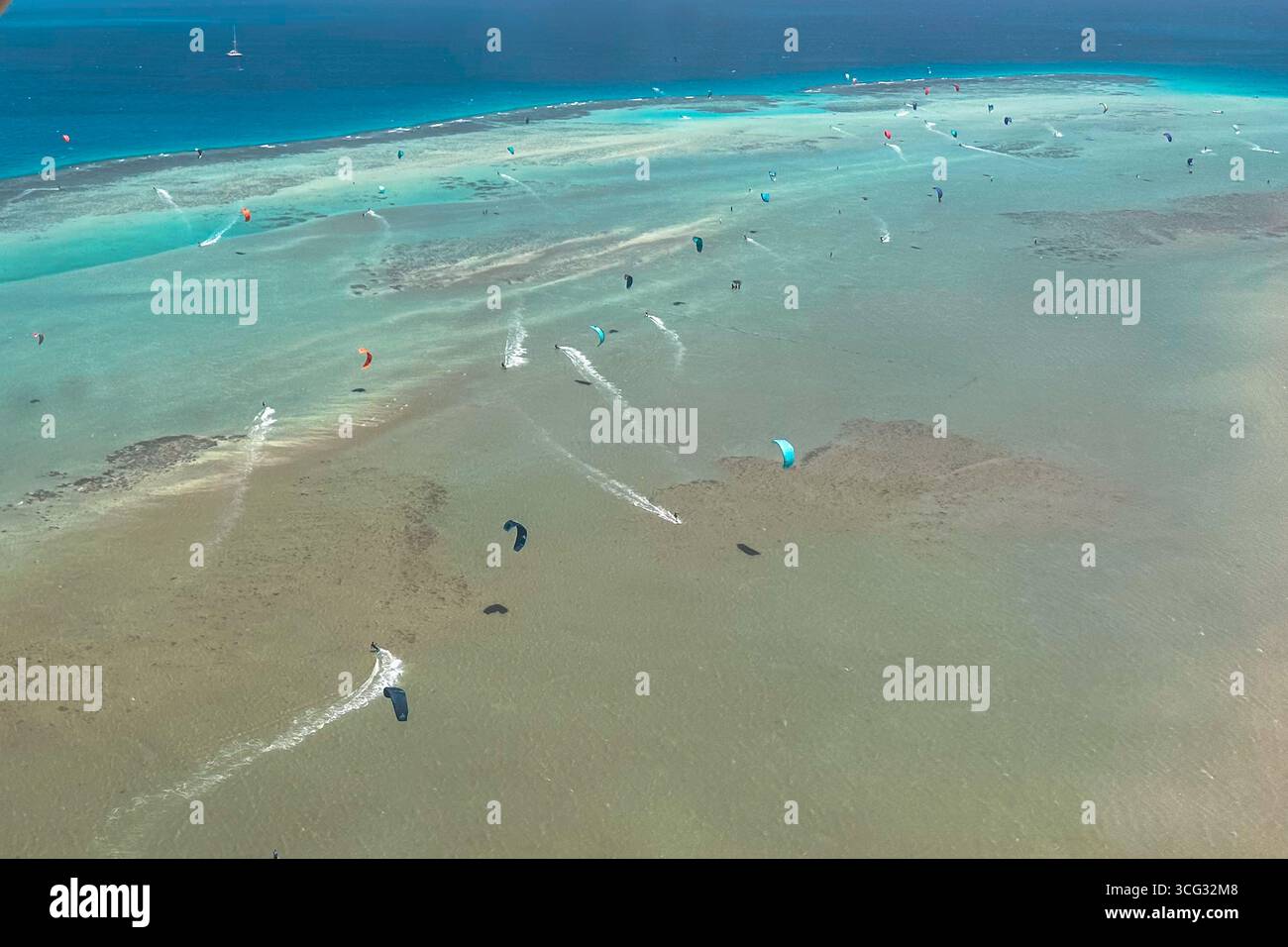 Vista aerea dei kitesurfer che ballano attraverso i fondali bassi, i loro aquiloni colorati un vibrante contrasto con le acque turchesi e i fondali sabbiosi, Gouna, Governatorato del Mar Rosso, Egitto. Foto Stock