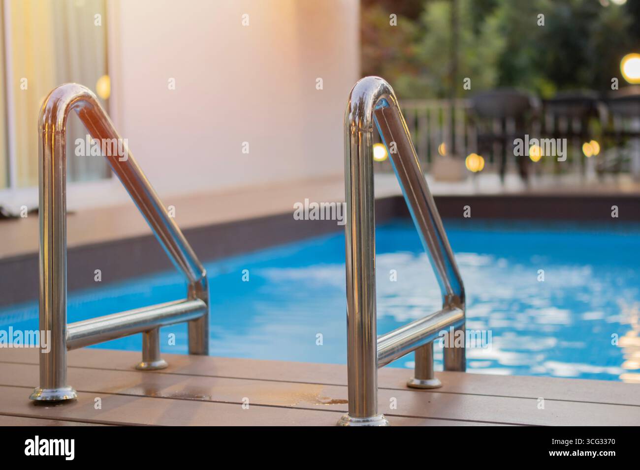Primo piano di scale metalliche nella piscina di fronte a una casa in un resort. Scala per accedere alla piscina. Foto Stock