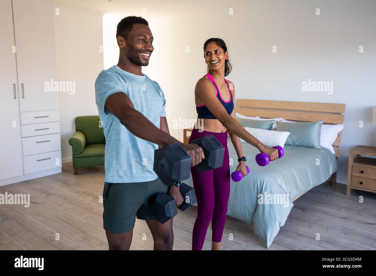 Diverse coppie che tengono i manubri mentre si allenano in camera da letto a casa Foto Stock