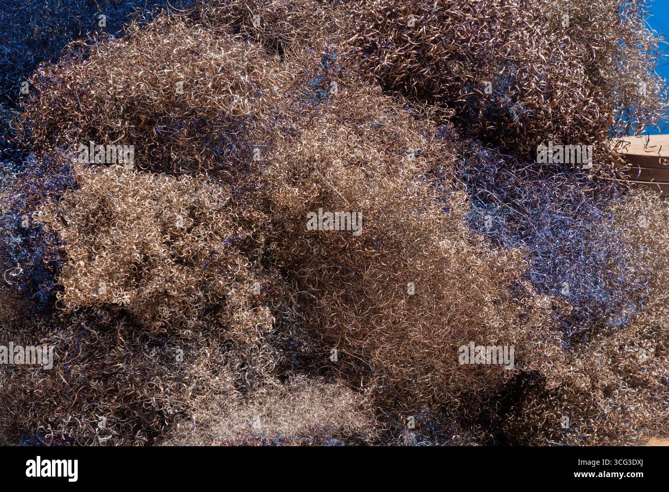Questa immagine mostra un grande mucchio di reti da pesca marrone e blu, mettendo in evidenza l'attrezzatura marina, la consistenza e il sostentamento costiero Foto Stock