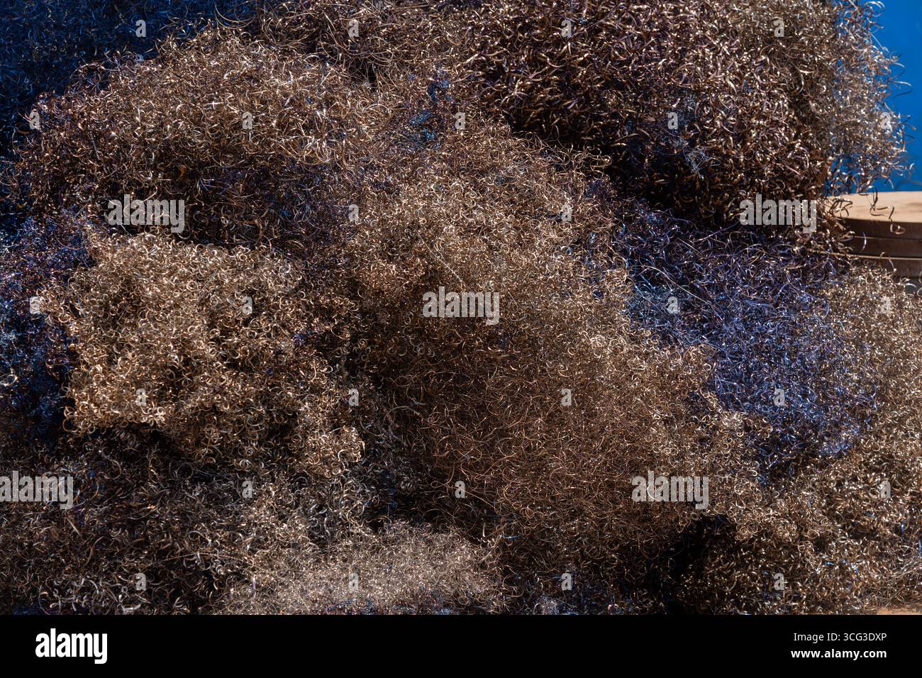 Questa immagine mostra un grande mucchio di reti da pesca marrone e blu, mettendo in evidenza l'attrezzatura marina, la consistenza e il sostentamento costiero Foto Stock