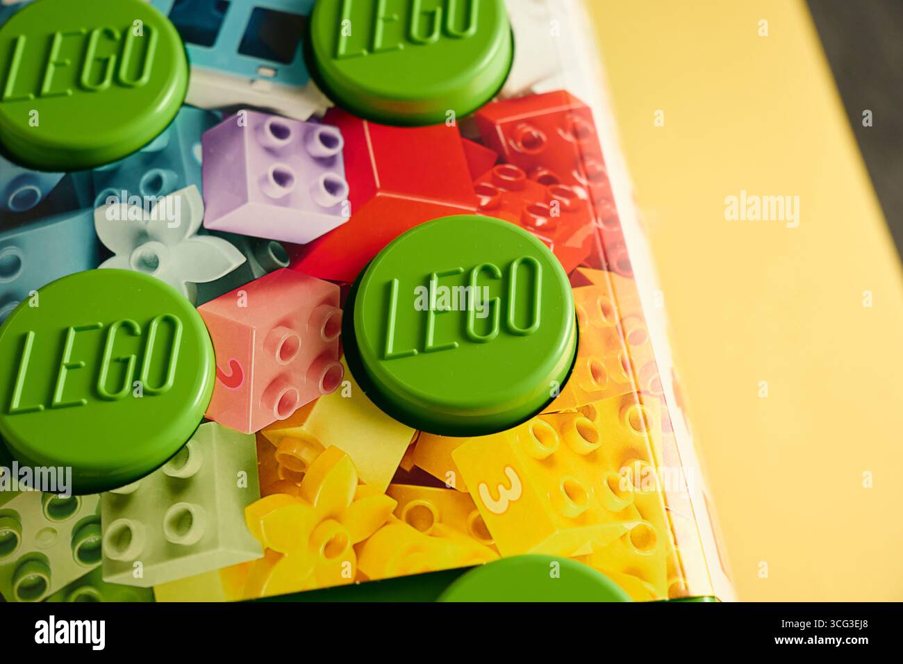 Tyumen, Russia - 8 luglio 2025: Il blocco Lego di costruzione verde si trova su uno sfondo colorato con disegni giocosi Foto Stock