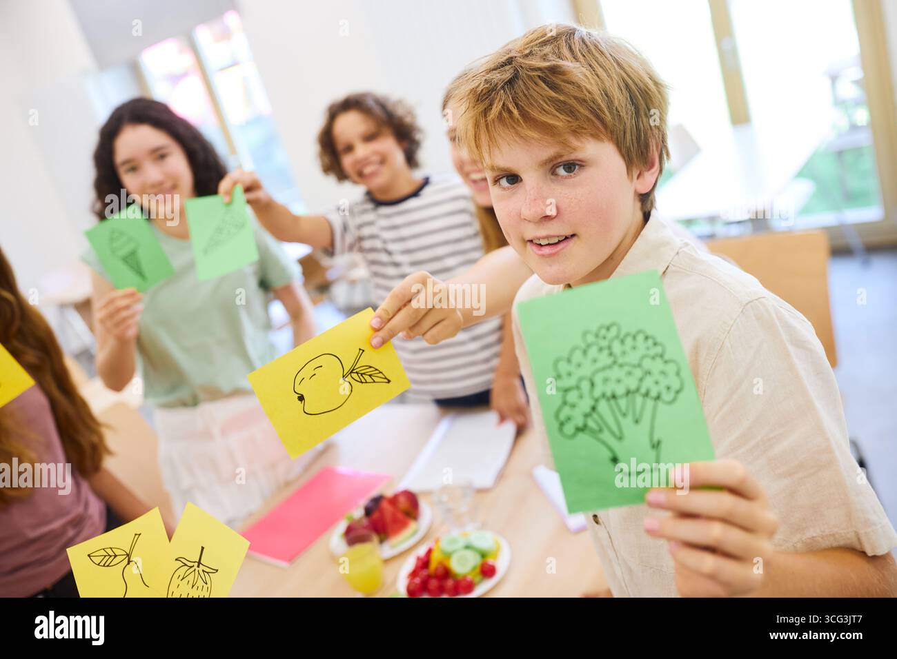 Un gruppo di bambini delle scuole si impegna in un progetto collaborativo, mostrando con entusiasmo disegni di cibi sani come parte di un divertimento ed educativo Foto Stock