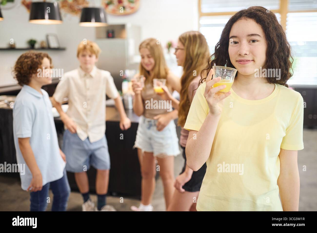 Gli adolescenti socializzano in una luminosa caffetteria scolastica, godendosi il succo di frutta e favorendo le amicizie. L'atmosfera riflette la gioventù, il tempo libero e il cameratismo Foto Stock