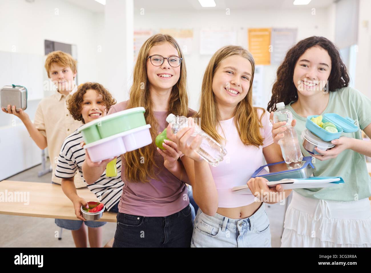 Un gruppo di studenti in una caffetteria che tiene dei contenitori riutilizzabili per il pranzo, che espone spuntini e bevande salutari. La scena mette in risalto la consapevolezza dell'ambiente, giovanotto Foto Stock