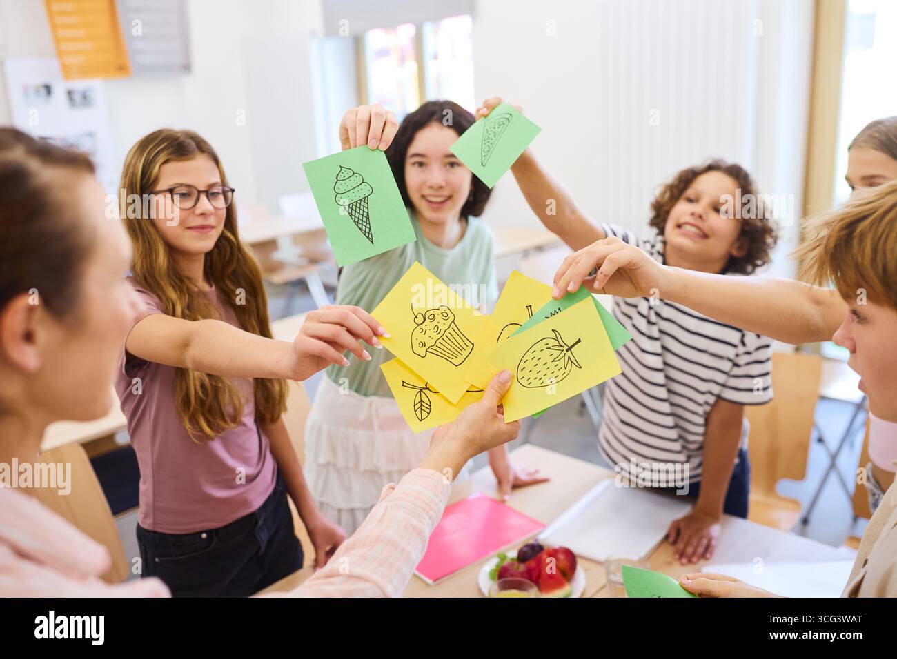 Gli studenti si impegnano in un ambiente collaborativo e creativo in classe, presentando carte artistiche con disegni, mostrando entusiasmo, lavoro di squadra, Foto Stock