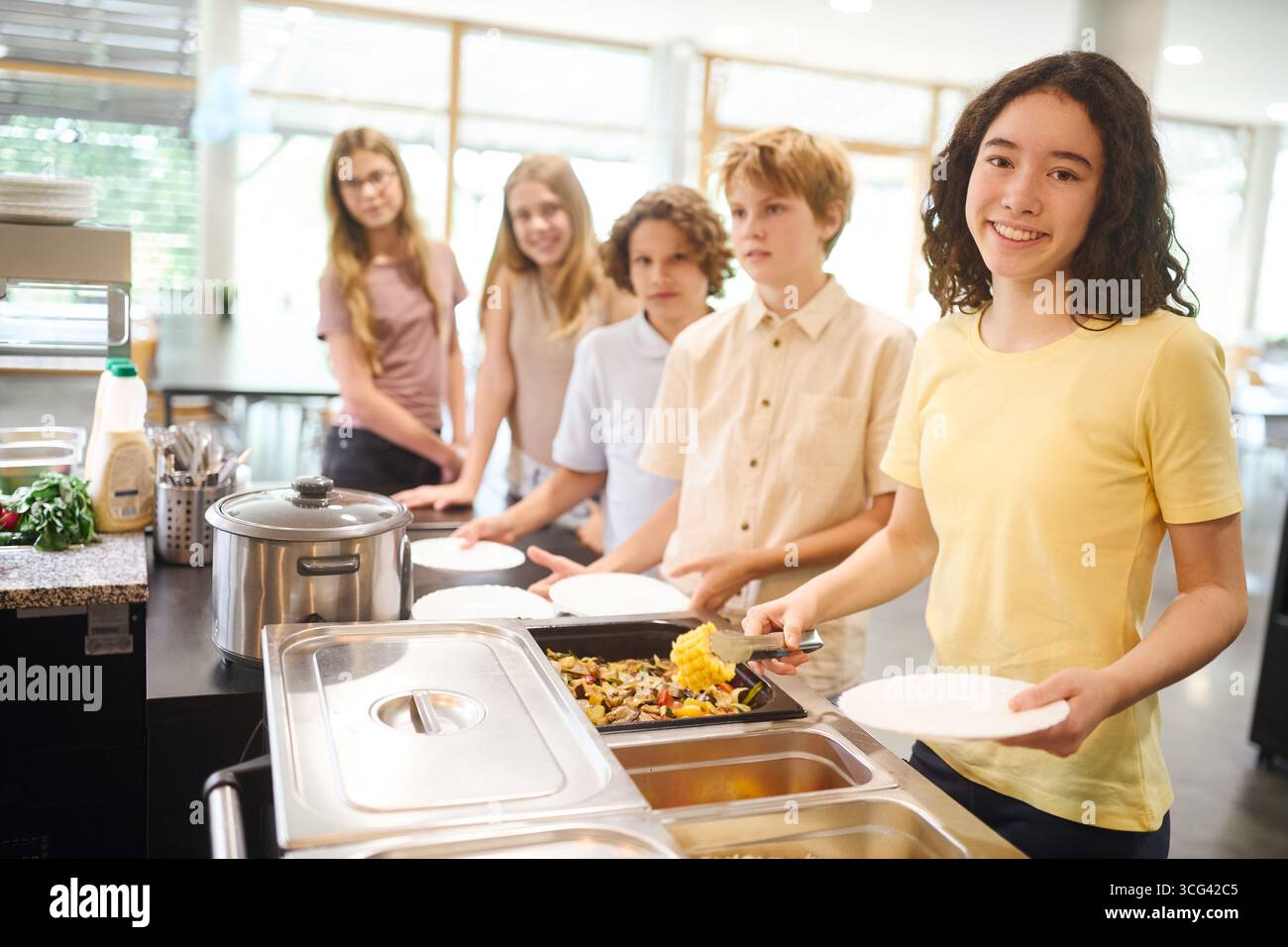 Gli studenti potranno gustare insieme un pasto preparato al momento in una luminosa e allegra caffetteria scolastica. Foto Stock