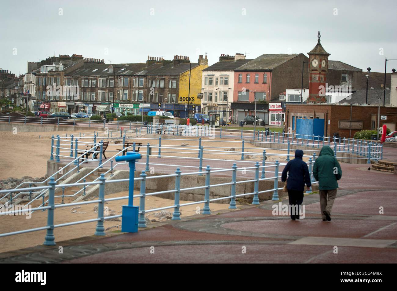 I pensionati hanno fatto una passeggiata in una giornata umida e ventosa a Morecambe Bay, Lancashire, Regno Unito Foto Stock