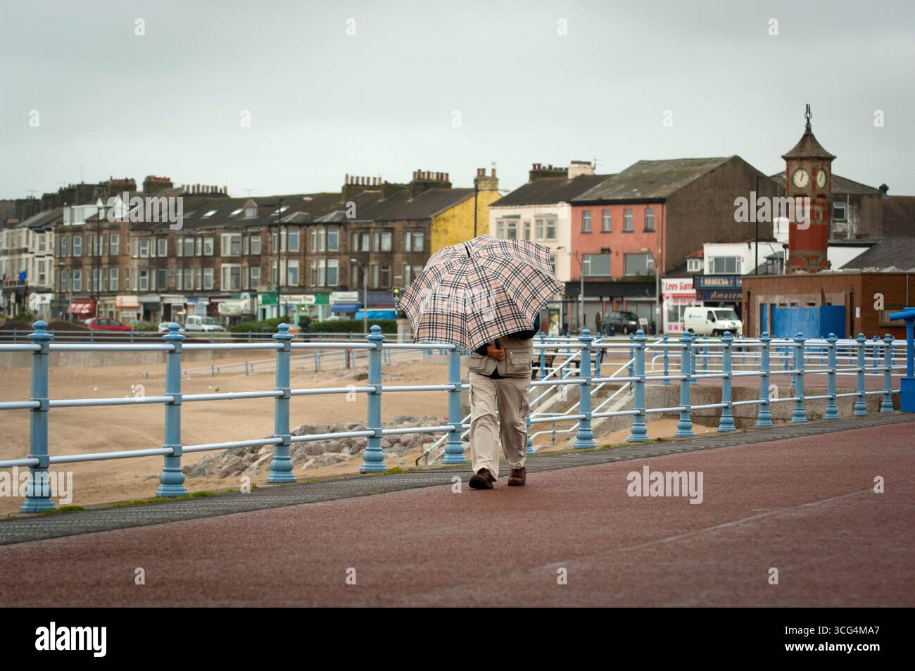 I pensionati hanno fatto una passeggiata in una giornata umida e ventosa a Morecambe Bay, Lancashire, Regno Unito Foto Stock