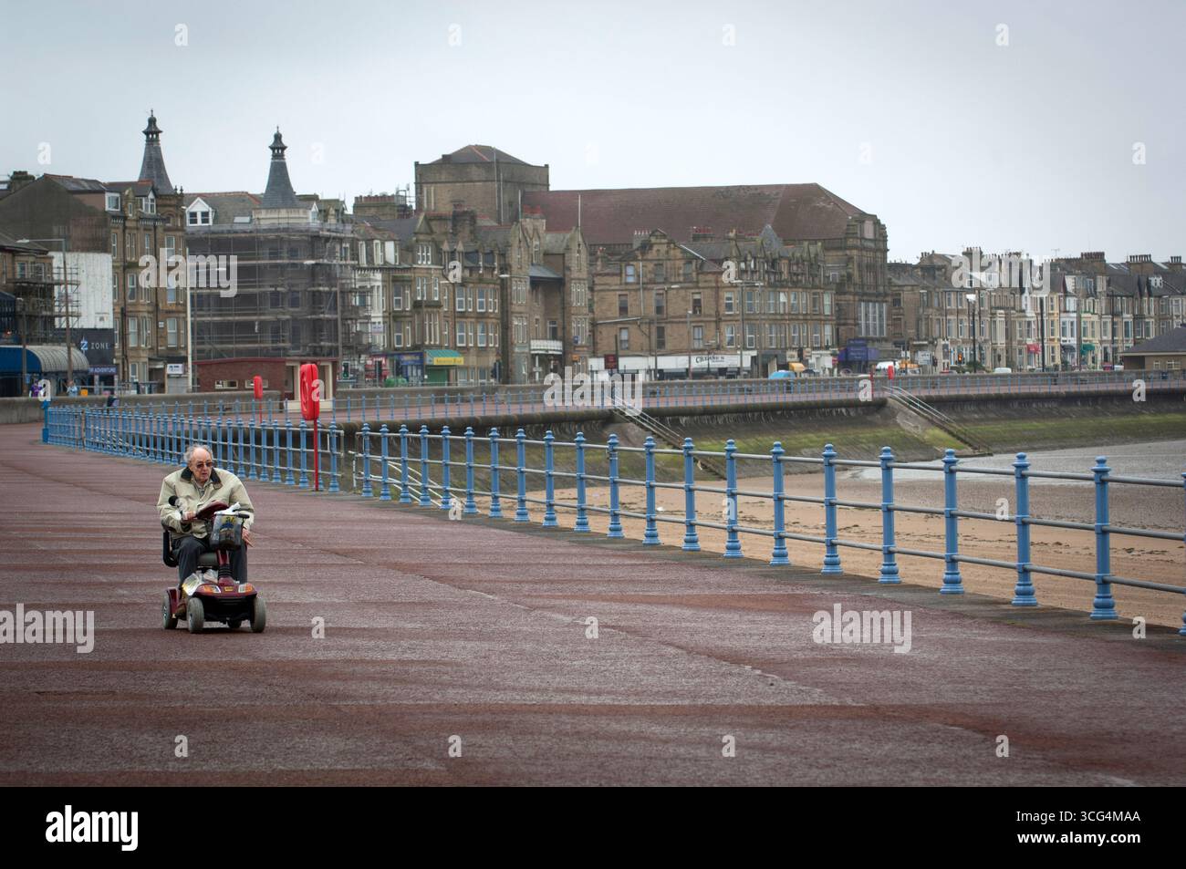 I pensionati hanno fatto una passeggiata in una giornata umida e ventosa a Morecambe Bay, Lancashire, Regno Unito Foto Stock