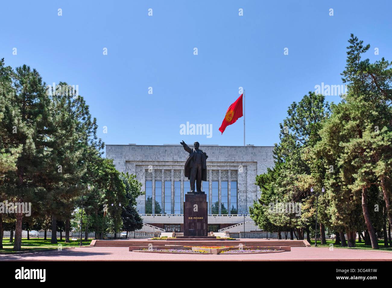 Kirghizistan, Bishkek - 12 luglio 2025: Statua di Lenin nella piazza centrale di Ala-Too con bandiera nazionale del Kirghizistan, edificio del Museo di storia statale a backgrou Foto Stock
