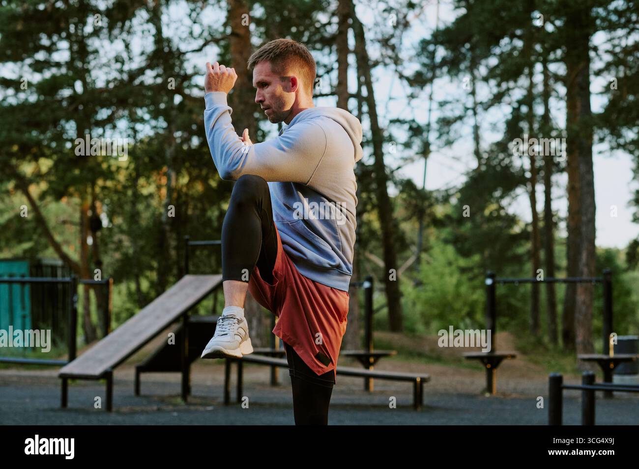 Uomo caucasico giovane adulto che si esercita all'aperto eseguendo un allenamento al ginocchio alto Foto Stock