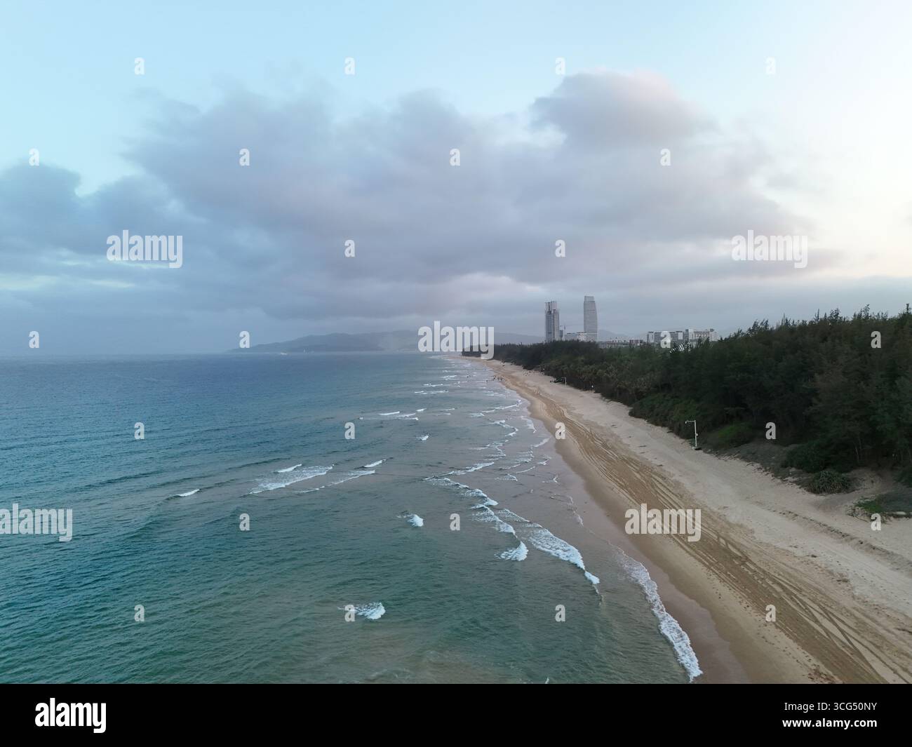 Vista aerea della costa di Sanya con oceano turchese, spiaggia di sabbia e lussureggiante foresta verde Foto Stock