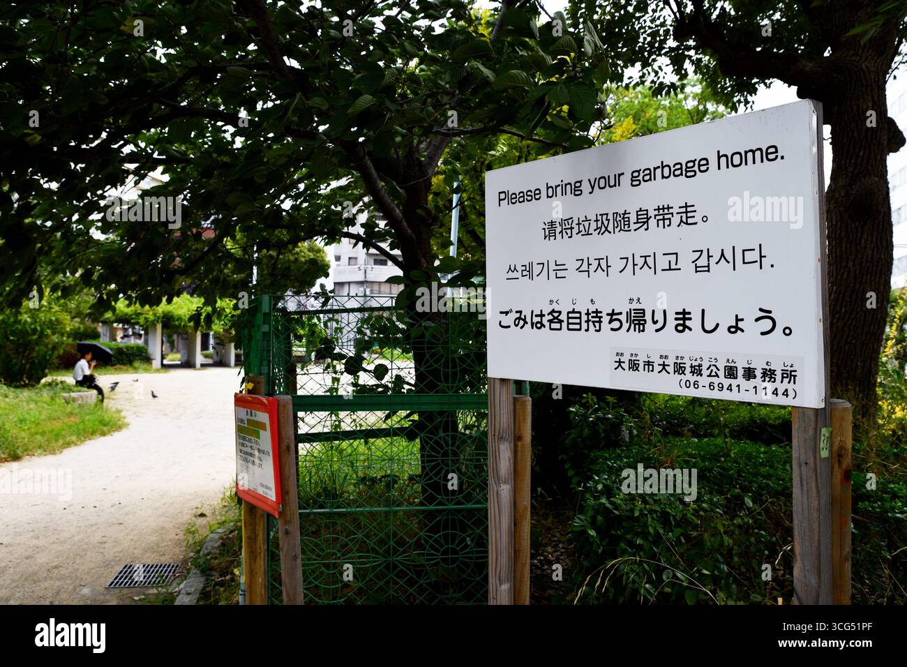 "Per favore portate la vostra spazzatura a casa" in un parco pubblico - scena di strada nella città di Osaka - Giappone Foto Stock