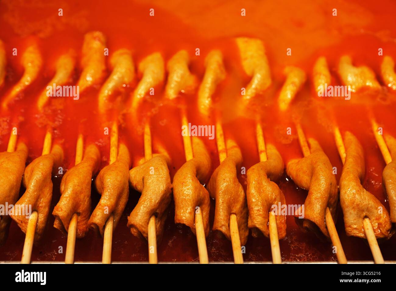 Primo piano di spiedini di torta di pesce coreana disposti in un ricco brodo rosso speziato Foto Stock