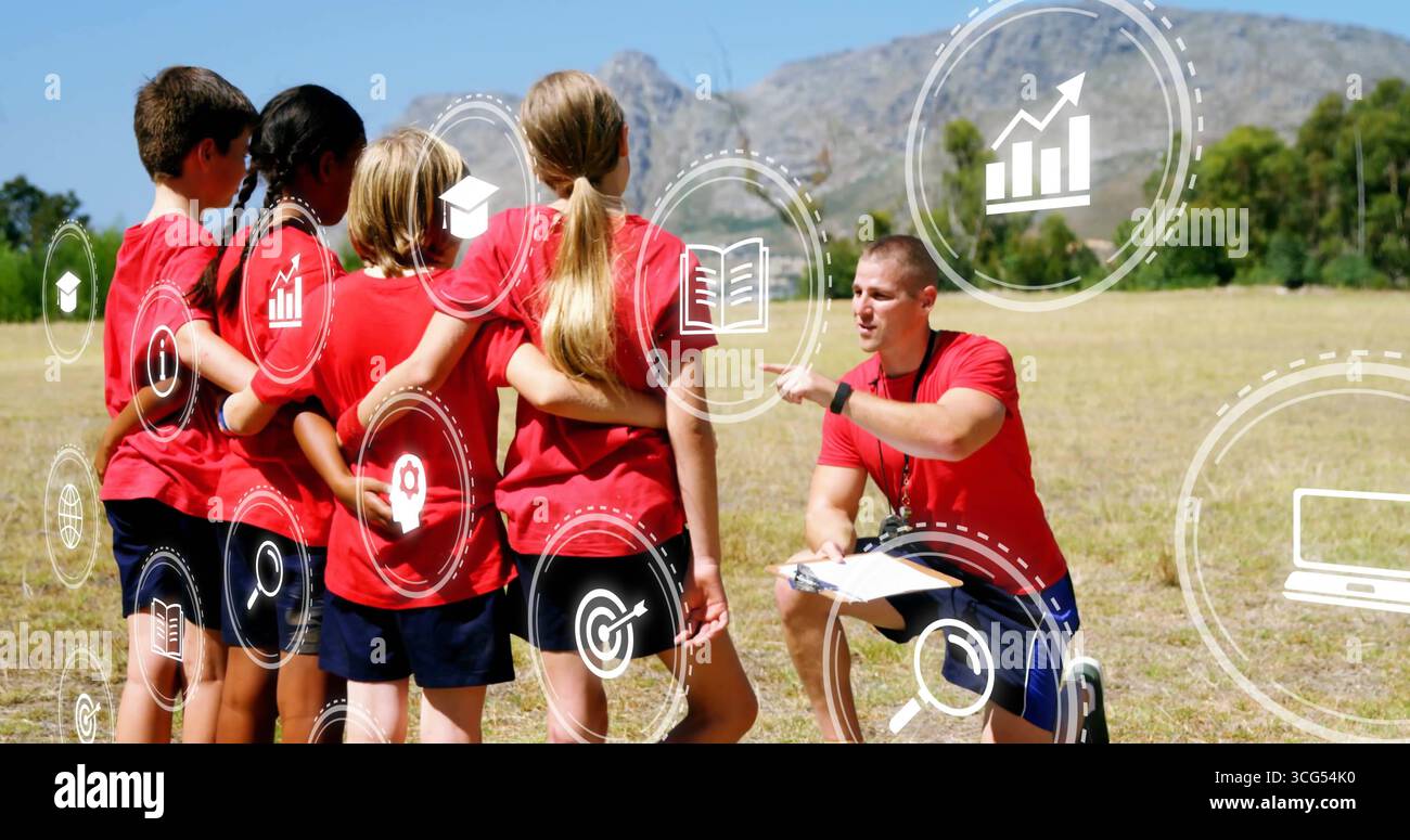Allenatore parlante inginocchiato con la squadra in maglie rosse che istruisce sul campo, con icone di fischio degli appunti Foto Stock