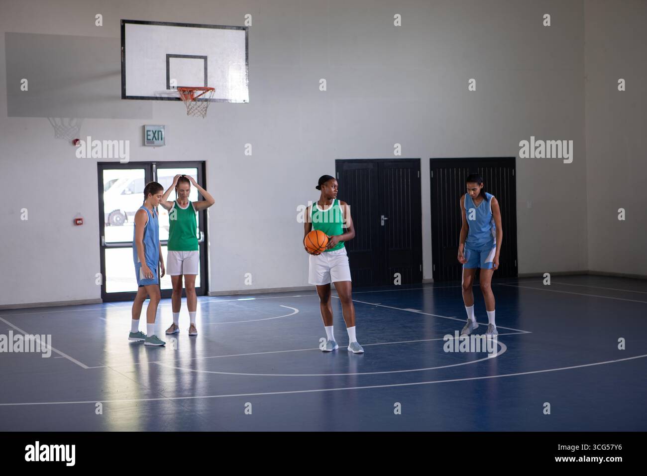 Diverse atlete si sfidano su un elegante campo da ginnastica con basket Foto Stock