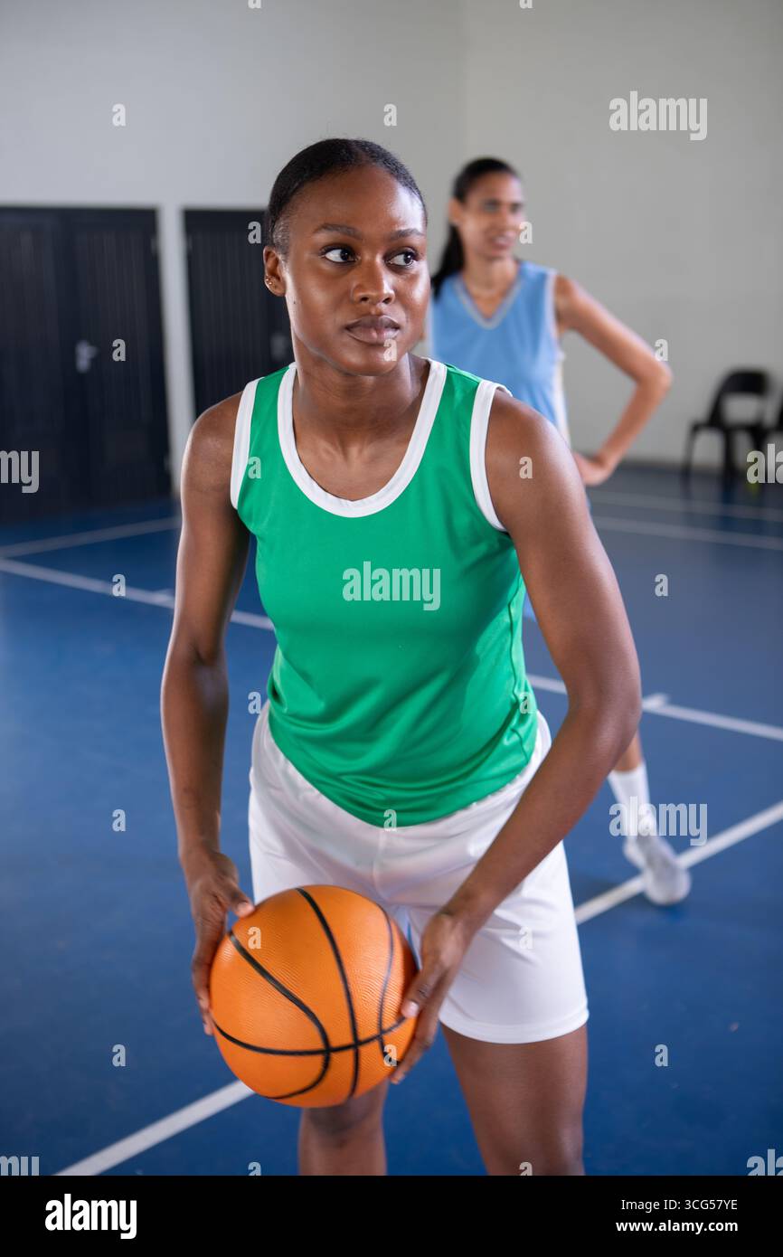 Diverse compagne di squadra che indossano maglie e pantaloncini da basket arancioni sulle linee blu del campo Foto Stock