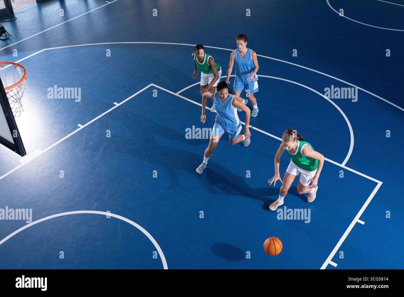 Diverse atlete di dribbling palla, difendendo vicino al cerchio sul campo con linee, rete, spazio copia Foto Stock