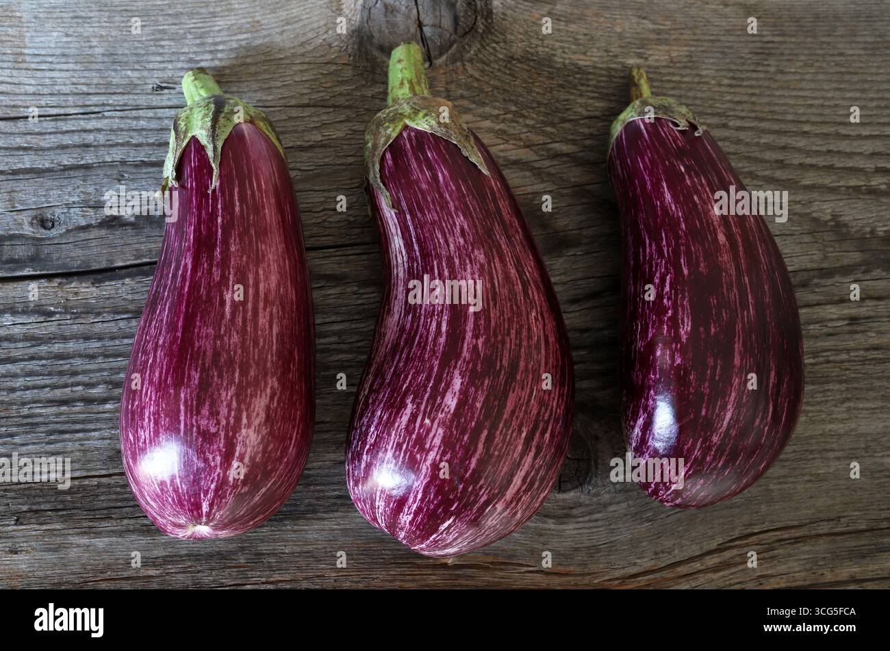 Melanzane fresche a strisce viola o melanzane isolate su fondo di legno. Cibo sano e vegetariano. Foto Stock