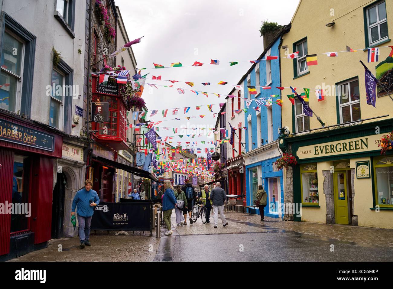 Una vivace scena di strada a Galway, in Irlanda, piena di edifici colorati e bandiere. Foto Stock