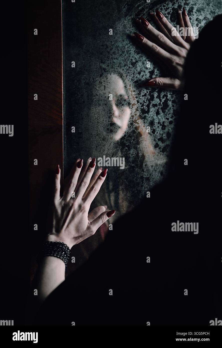 Scena horror: Riflesso sfocato della ragazza fantasma nel vecchio specchio sporco Foto Stock