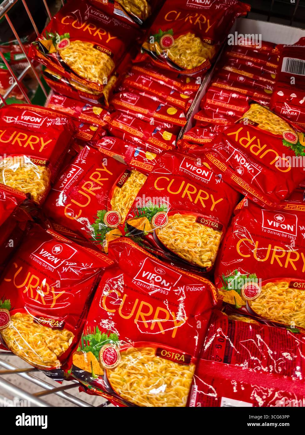 Wroclaw, Polonia - 16 agosto 2025: File di vivaci pacchetti di spaghetti rossi si trovano impilati in un corridoio di alimentari, mostrando il loro sapore al curry. Foto Stock