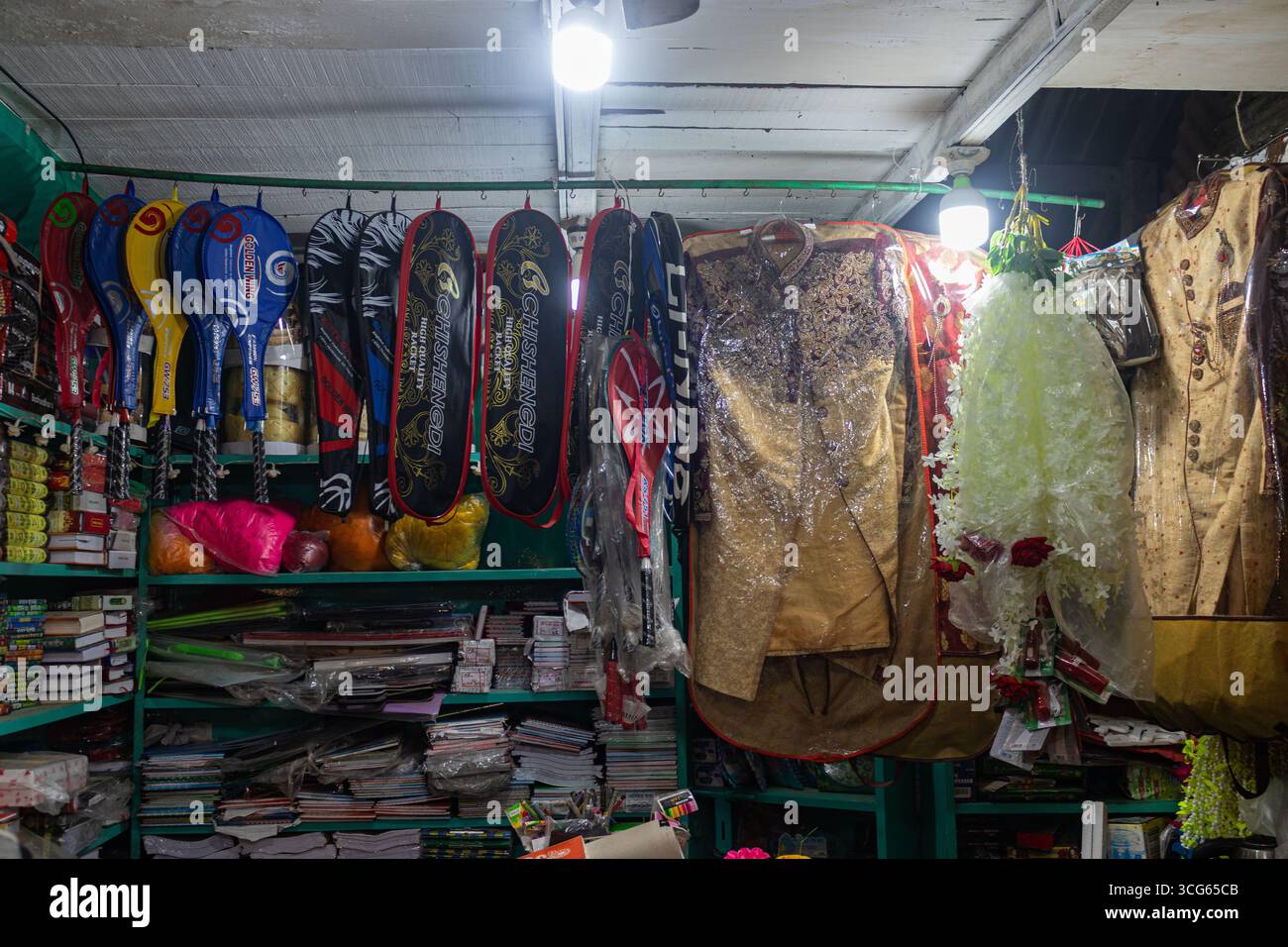Racchette da badminton colorate esposte insieme a un abbigliamento da sposa tradizionale all'interno di un vivace negozio interno. Una combinazione unica di attrezzature sportive Foto Stock