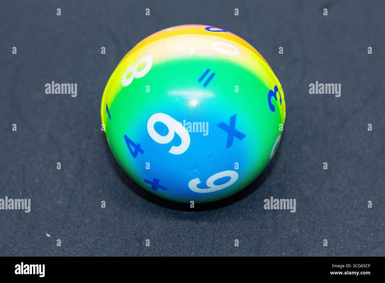 Colorata pallina di matematica educativa con numeri e simboli, visualizzata su sfondo scuro. Ideale per l'apprendimento della prima infanzia, l'educazione basata sul gioco Foto Stock