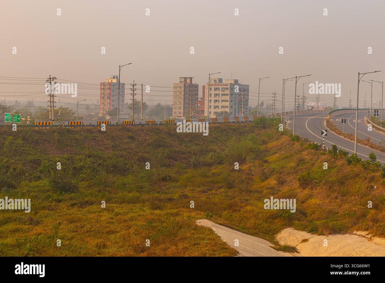 Cantiere in costruzione sulla Dhaka-Mawa Highway con vista libera della strada, asfalto senza traffico, barriere stradali e coni di sicurezza sotto il cielo blu. Infrastruttura Foto Stock